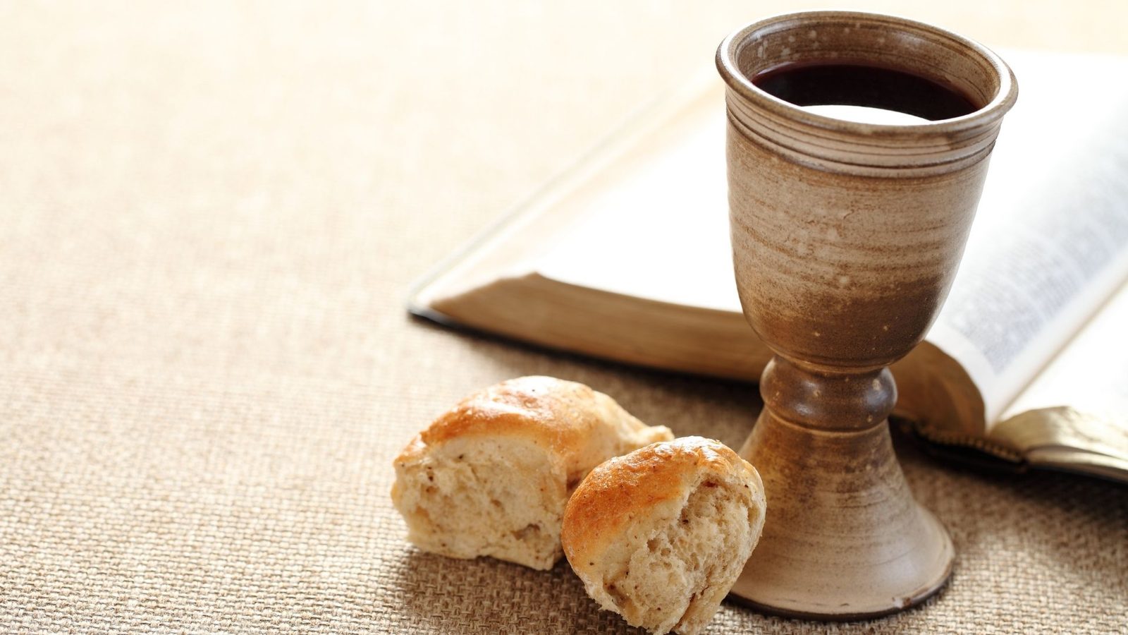 Bread and a cup of wine beside an open bible